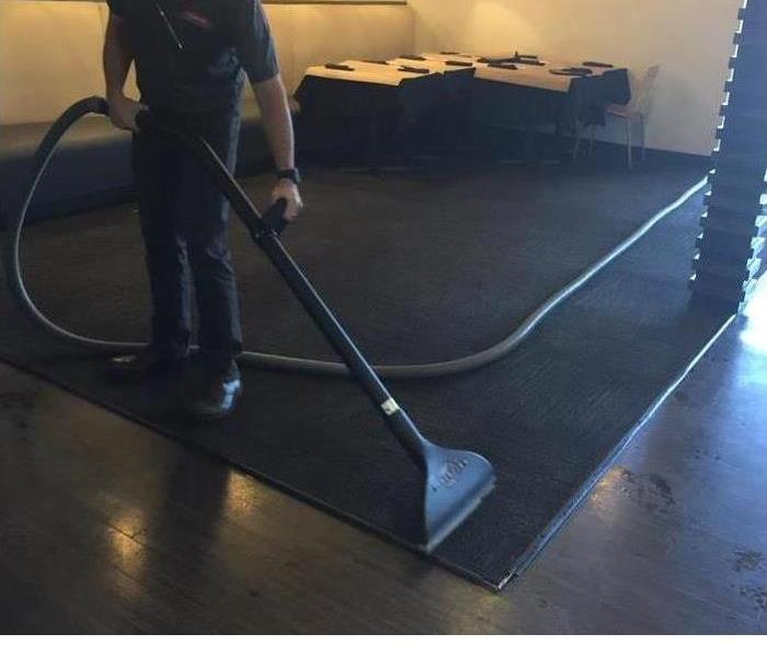 A room with a man sweeping up water.